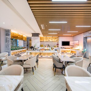 A modern restaurant with marble flooring, wooden ceiling panels, and a central bar area. - Atour Hotel (Ma'anshan)