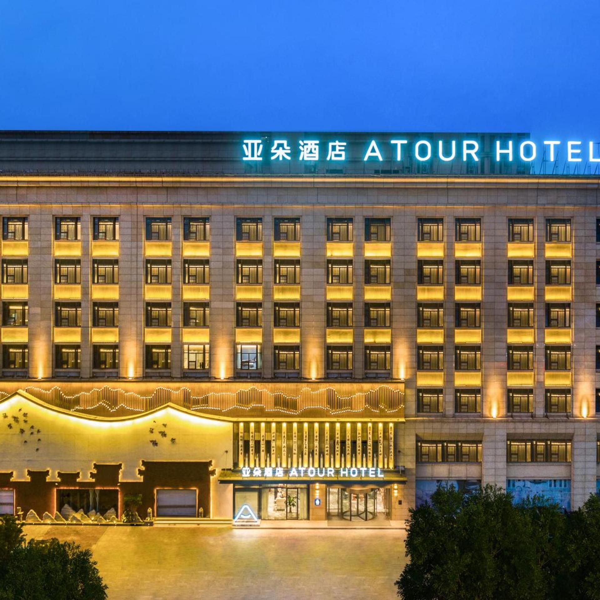 Ein mehrstöckiges Hotel mit markantem Eingang und beleuchteter Beschilderung.
