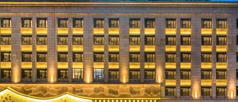 Un hotel de varios pisos con una entrada destacada y señalización iluminada.