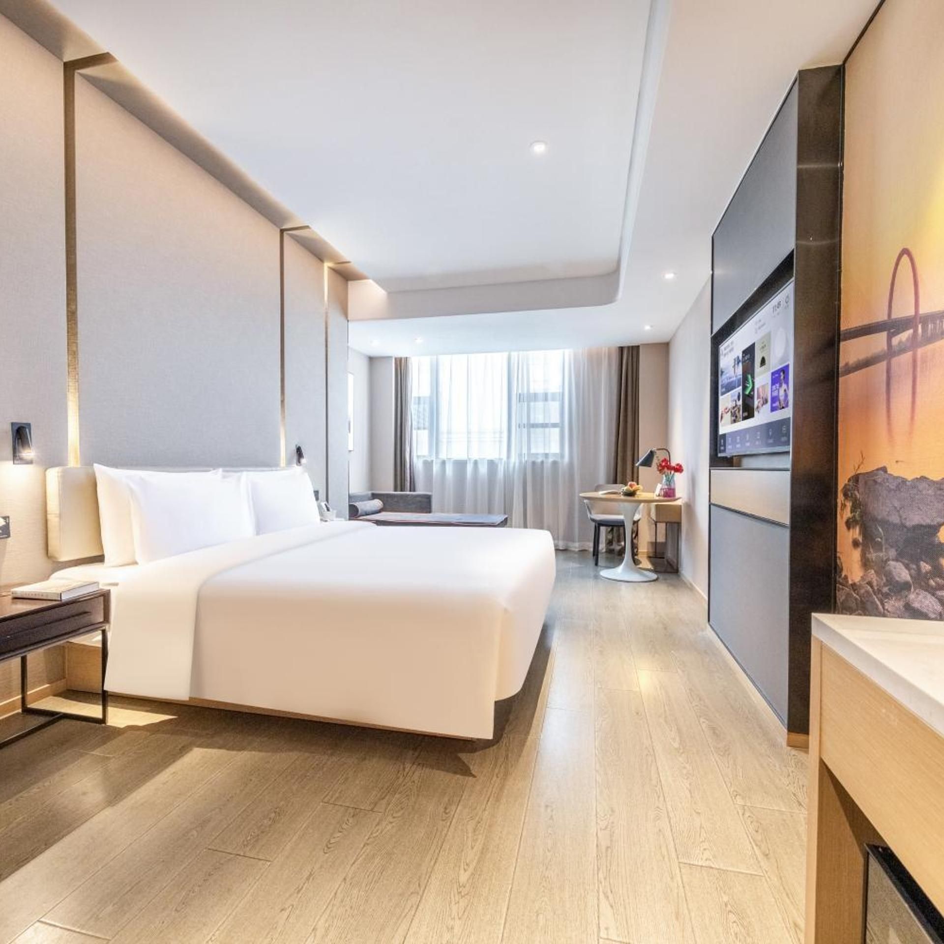 Habitación de hotel con una cama grande, mesitas de noche, un escritorio con una silla, un televisor y una ventana con cortinas.