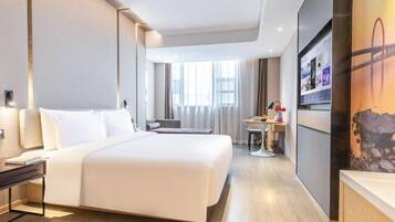 Habitación de hotel con una cama grande, mesitas de noche, un escritorio con una silla, un televisor y una ventana con cortinas.