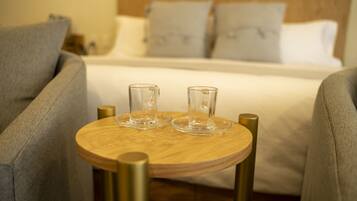 A neatly arranged bedroom with a bed, two bedside tables, and a small wooden table with two glasses.