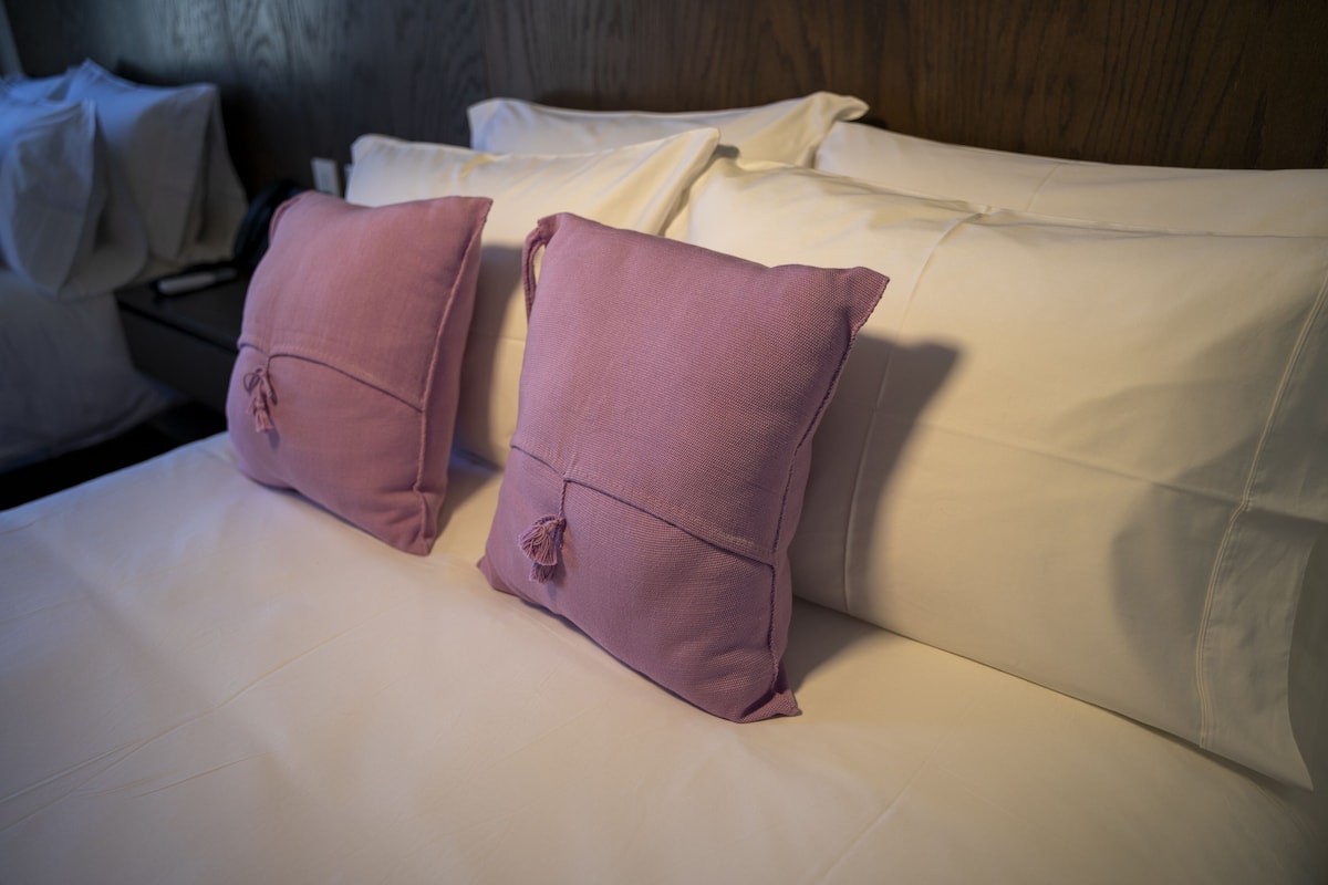 Una cama con dos almohadas y una mesita de noche.