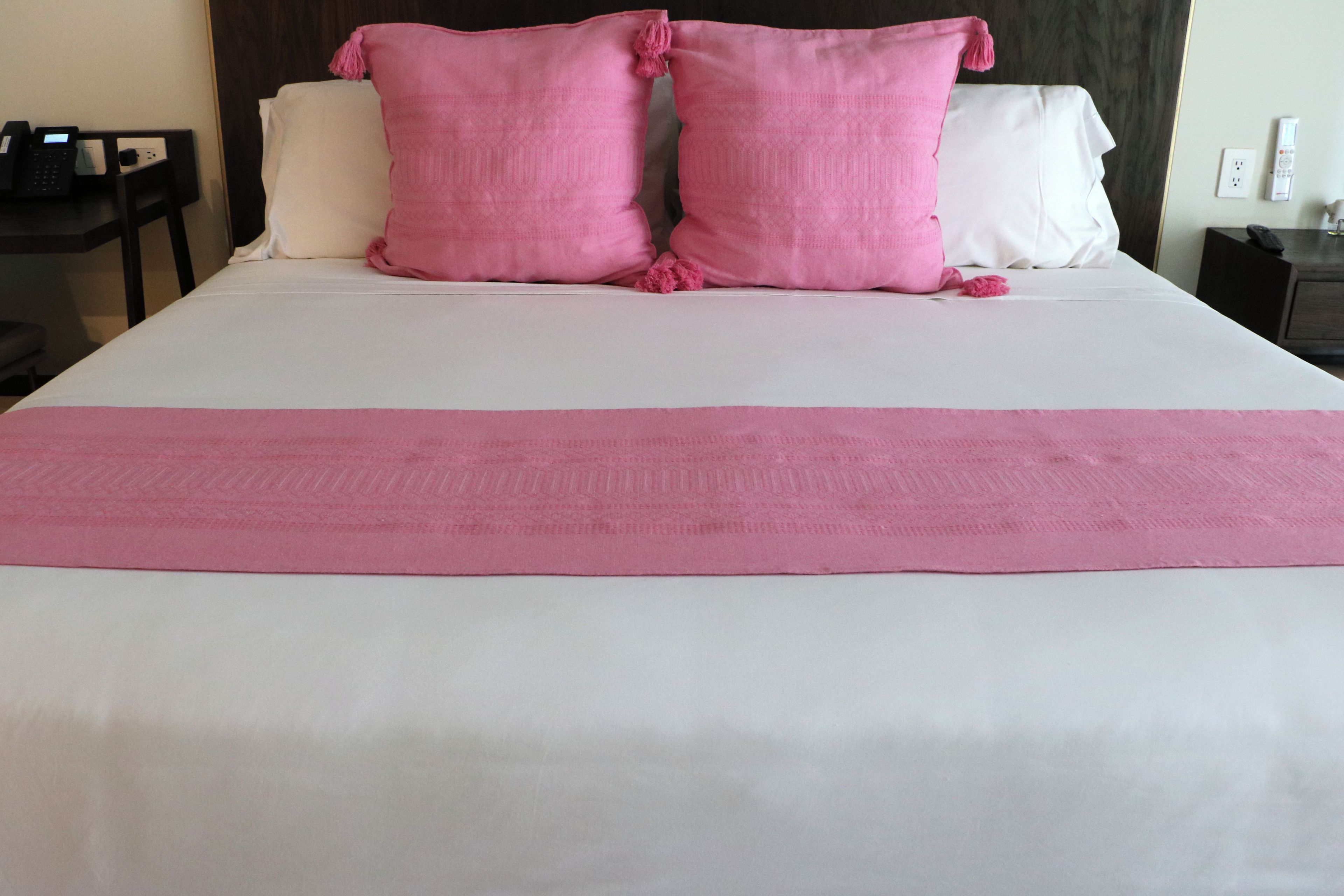 A bed with white bedding and two large pink pillows.