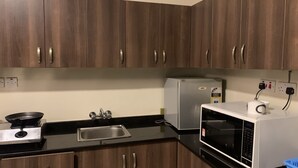 Une cuisine avec des meubles en bois, un évier en acier inoxydable, un four à micro-ondes et un réfrigérateur.