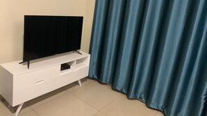 Un meuble blanc pour télévision à écran plat, doté d’un petit tiroir et d’une télécommande.