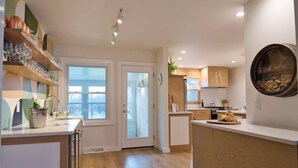 A modern kitchen with a central island, wooden cabinets, and a large window.
