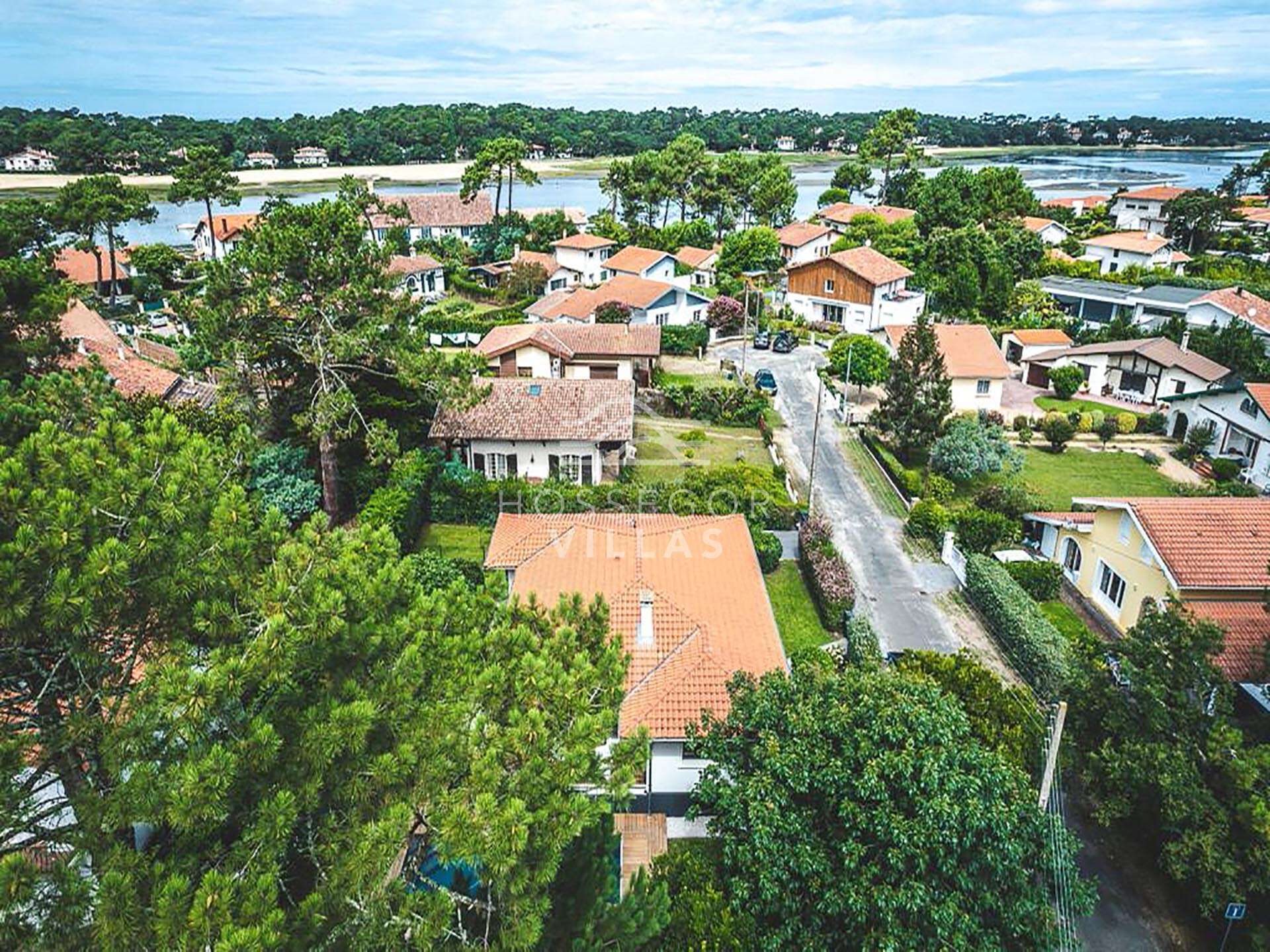 A residential area with houses, a road, and a body of water in the background.