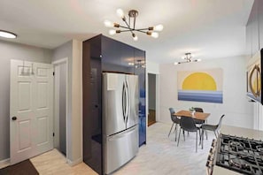 A modern kitchen with a stainless steel refrigerator, a gas stove, and a dining area with a table and chairs.