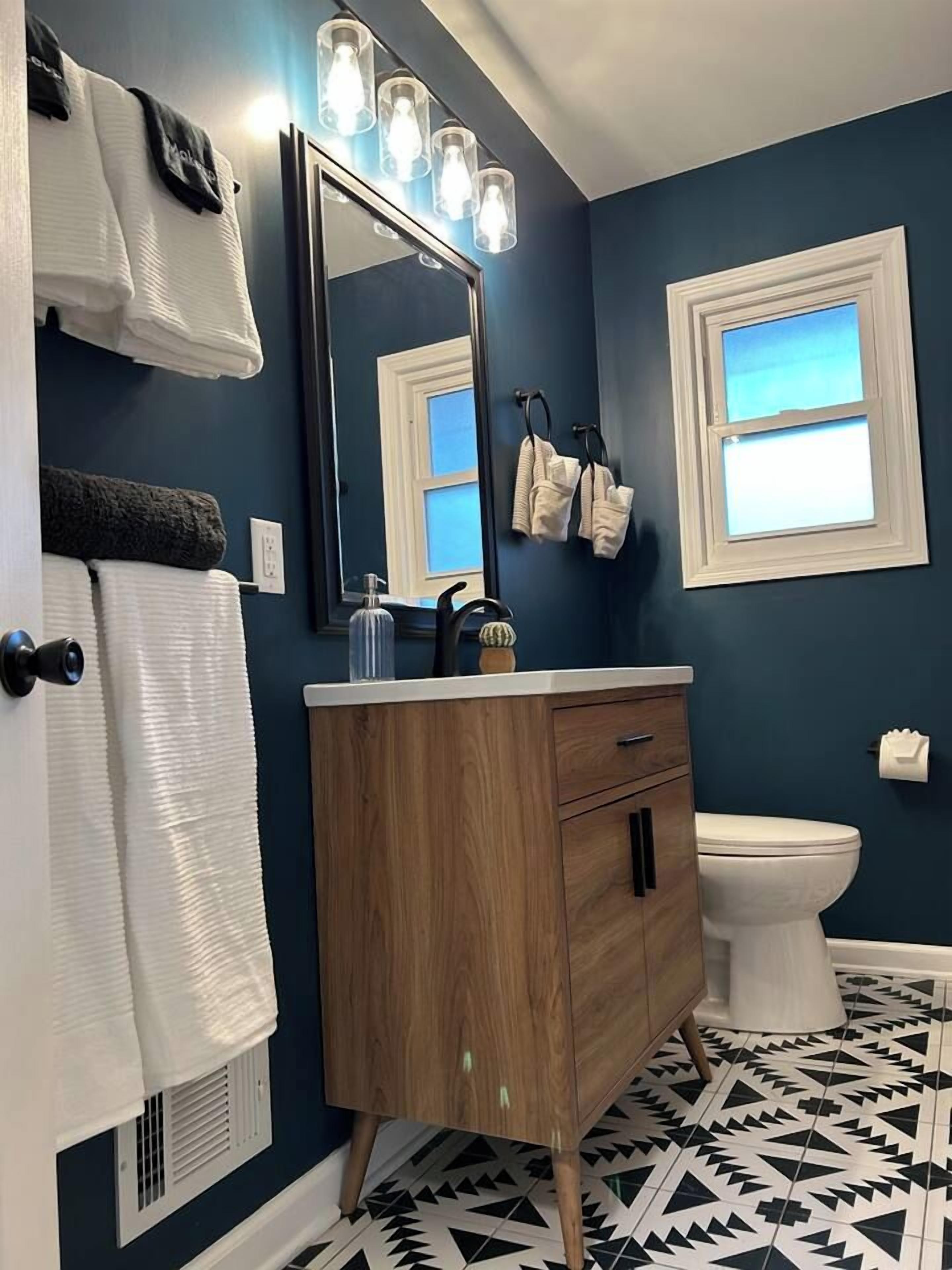 Un baño con tocador de madera, inodoro blanco y espejo con iluminación.