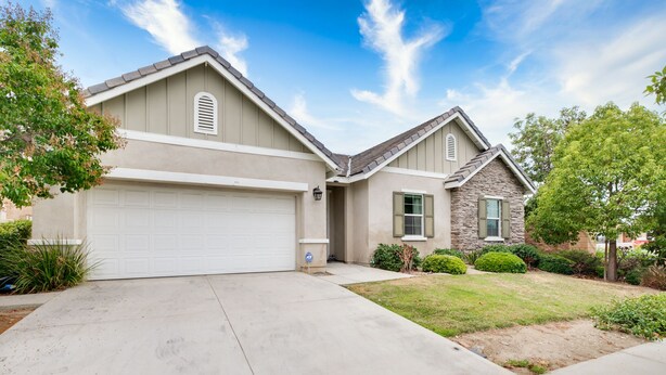 A two-story house with a garage, a stone exterior, and a well-maintained lawn.