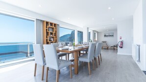 A modern dining area with a large table, chairs, and a view of the ocean. - Dream House by Atlantic Holiday (Ponta Delgada)
