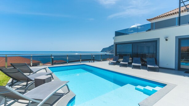 A modern pool area with lounge chairs and a view of the ocean. - Dream House by Atlantic Holiday (Ponta Delgada)