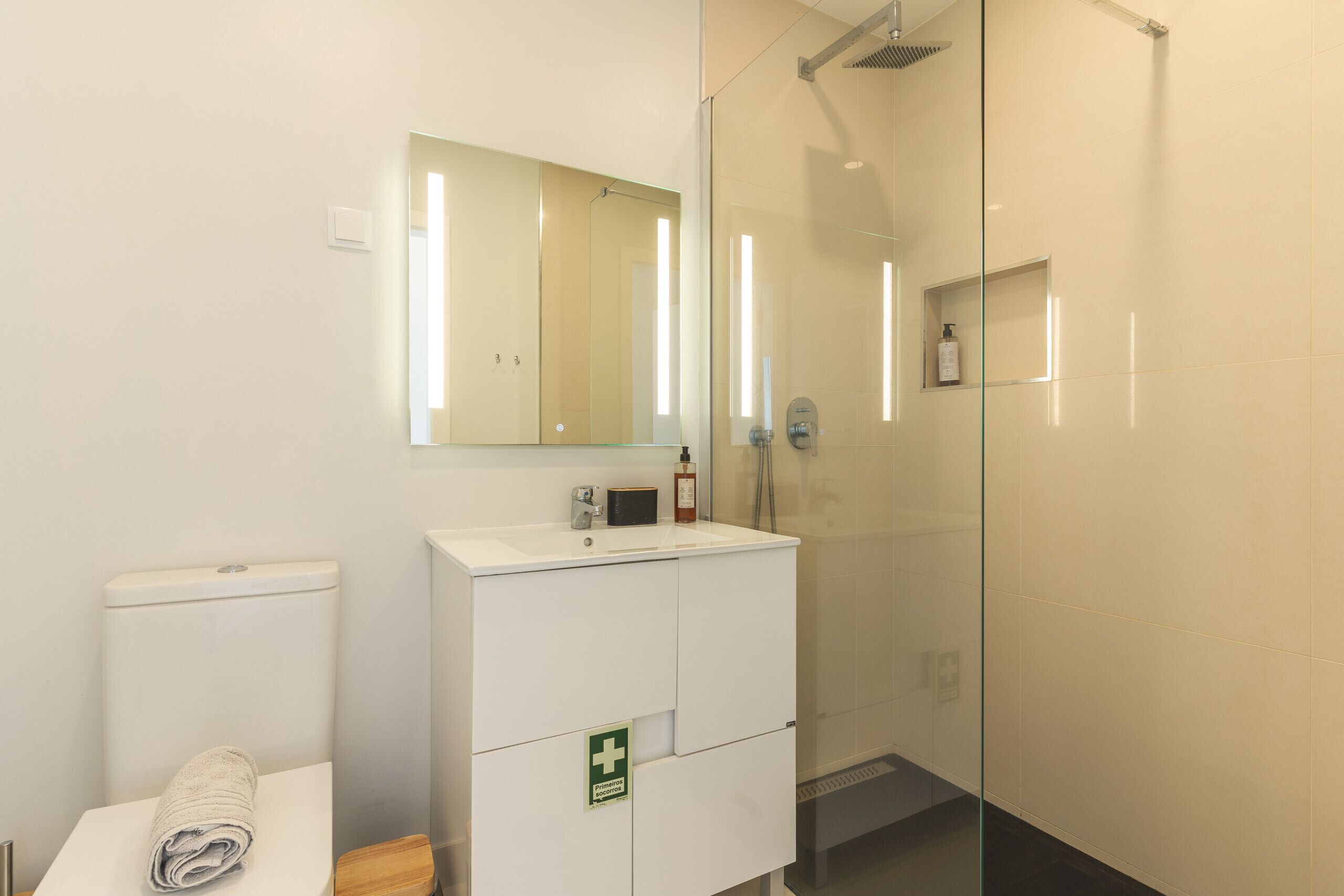 Et badeværelse med toilet, vask, spejl og brusebad.