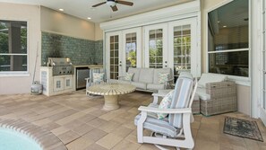 A patio with a grill, seating, and a stone wall.