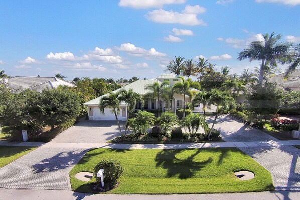 A well-maintained residential area with a house surrounded by lush greenery and palm trees. - Enjoying paradise on Marco Island with direct access! (Marco Island)