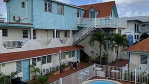 Un edificio de varios pisos con piscina, mobiliario exterior y una escalera que conduce a los pisos superiores.