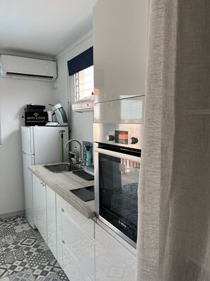 Una cucina compatta con forno integrato, lavello e microonde.