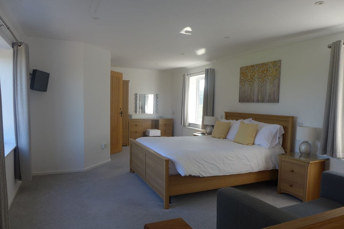 A bedroom with a wooden bed, bedside tables, a mirror, and a window with curtains.