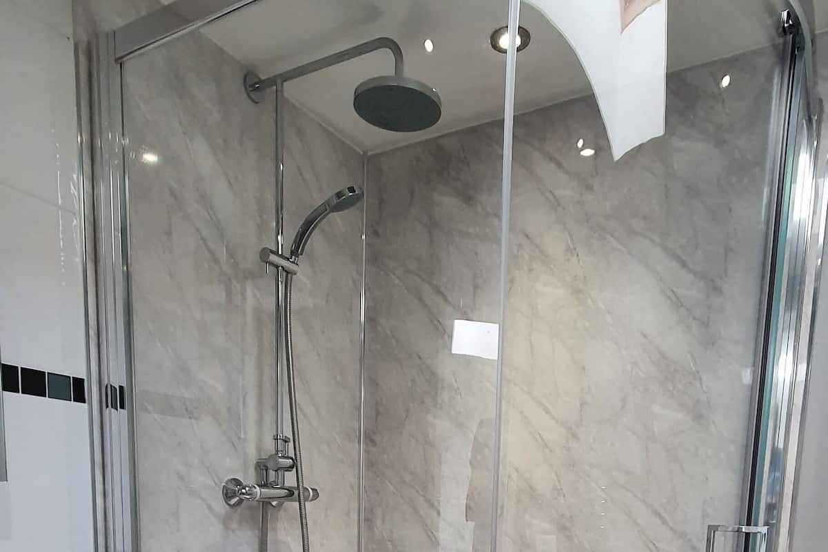 A modern bathroom with a glass-enclosed shower, a white sink, and a white chair.