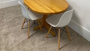 A dining area with a round wooden table and four white chairs. There is a framed picture of the Eiffel Tower on the wall. - Hyde Park Hyde Out Apt 3 (Boise)