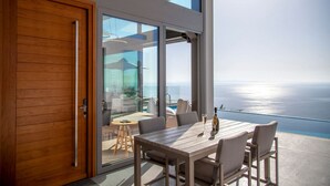 Une chambre moderne dotée d’une grande porte-fenêtre coulissante donnant sur un balcon avec vue sur l’océan.