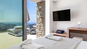 A hotel room with a bed, a TV, and a view of the sea. - Syvota 03 Sunset 2B Isidora (Igoumenitsa)