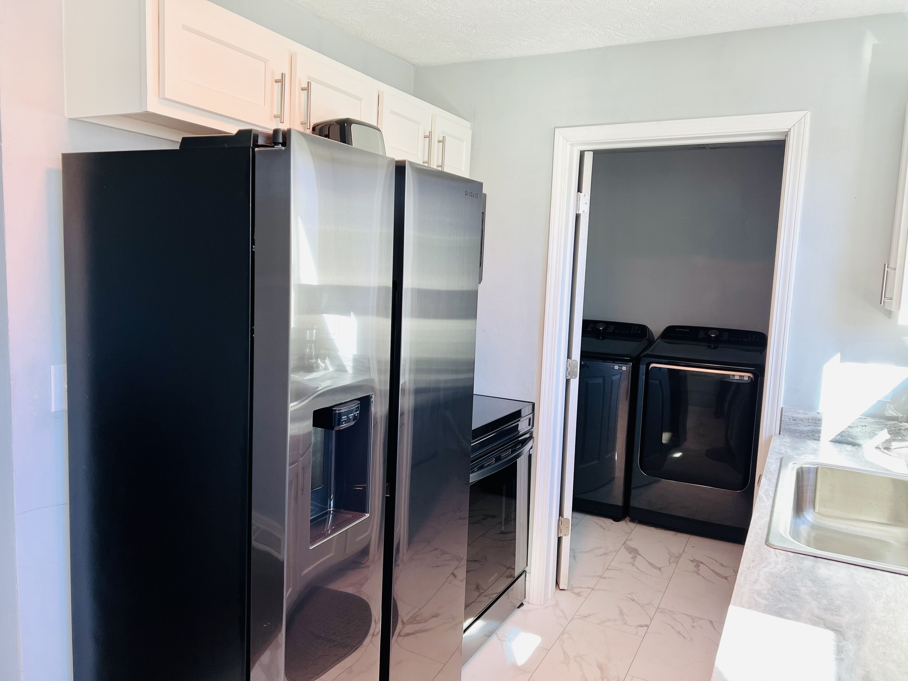 A kitchen with a black refrigerator, a microwave, and a dishwasher.