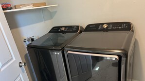 Two front-loading washers with stainless steel controls, placed next to a white door in a laundry room. - Remodeled townhouse - 5 mins from Shawnee Sports Complex! (Dunbar)