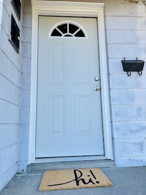 Welcome to a charming entrance with a semi-circular window above the door and a friendly doormat at its base.