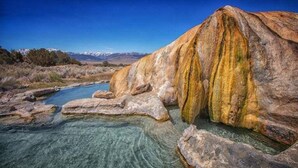 A natural landscape with a river, clear water, and a large rock formation.