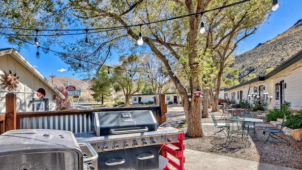 A backyard with a barbecue grill, outdoor seating, and a mountain backdrop.