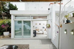 A modern house with a glass door entrance, a patio area, and a staircase leading to an upper level. - Villa Koki Zantos Sea View  (Zakynthos)