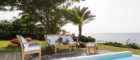 A poolside area with lounge chairs and a view of the sea.