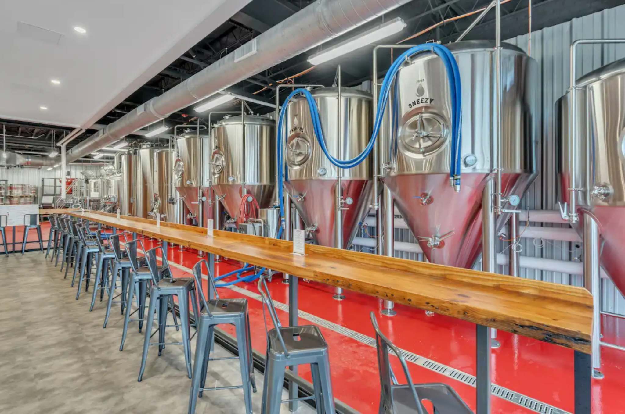 Een brouwerij met roestvrijstalen tanks en een lange bar met krukken.