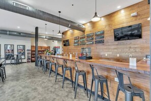 A modern bar area with a wooden counter, metal stools, and a menu board.