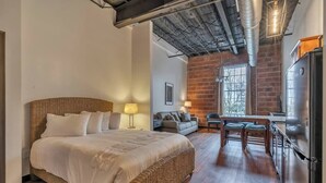 A bedroom with a large bed, a sofa, a dining table, and a kitchen area with a refrigerator. - 1 Bedroom @ Grand Strand Brewery 203 (Myrtle Beach)