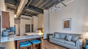 A modern kitchen with a bar area, a sofa, and a framed picture on the wall. - 1 Bedroom @ Grand Strand Brewery 203 (Myrtle Beach)