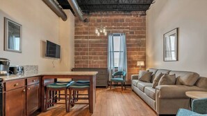 A compact living space with a kitchen area, a dining table with chairs, a sofa, and a small round table.