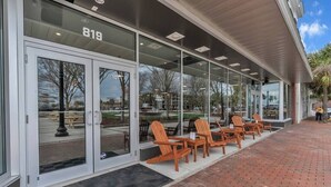A building with a glass entrance, numbered 819, and outdoor seating with wooden chairs.