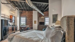 Un dormitorio con una cama grande, un escritorio y una kitchenette.