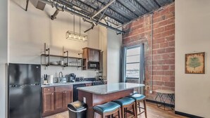 Una cocina moderna con una isla grande, taburetes de madera y una pared de ladrillo.