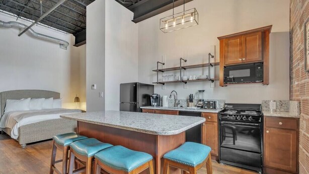 A compact kitchen with a central island, built-in appliances, and wooden bar stools.