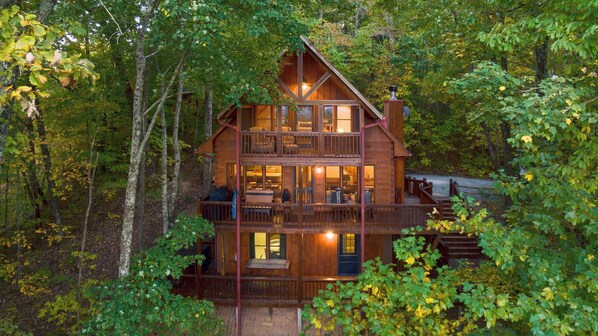 A two-story log cabin with a balcony and a fireplace, surrounded by dense forest. - Leola Lodge- Upscale escape, mtn views & hot tub (Blue Ridge)