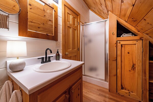 A bathroom with wooden cabinetry, a white sink, a mirror, and a towel rack.