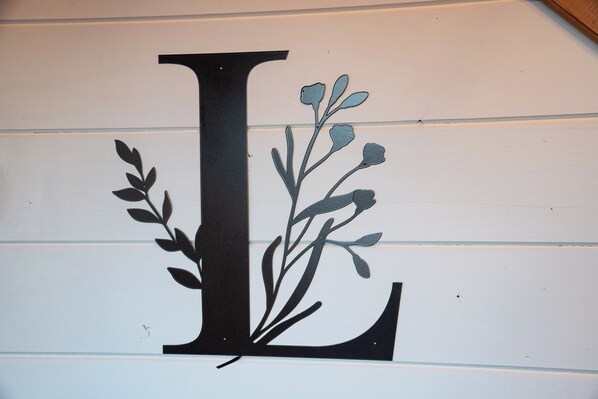 A wall with a large black letter 'L' and a decorative floral design.