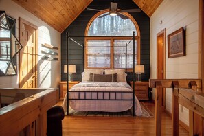 A bedroom with a large bed, wooden walls, a sloped ceiling, and a window with blinds. - Leola Lodge- Upscale escape, mtn views & hot tub (Blue Ridge)