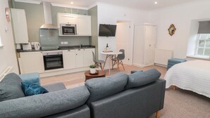 A compact living space with a kitchenette, a dining area, and a bedroom.