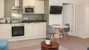 A compact kitchen with a microwave, oven, and a small dining area with a table and chairs.