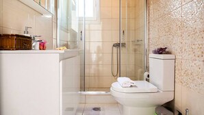 Une salle de bain moderne avec une douche à parois de verre, des toilettes blanches et un lavabo avec un meuble-vasque en bois.